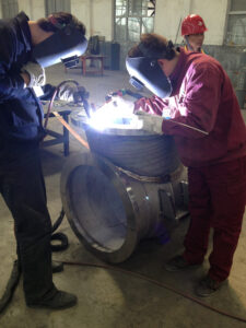 Two men welding a custom titanium pipe